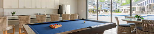 a pool table in a clubhouse with a view of a swimming pool