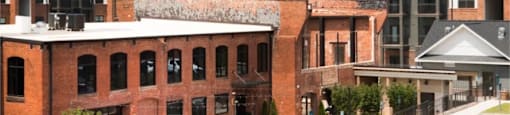 A water tower with a bird on it is behind a building with a brick facade.