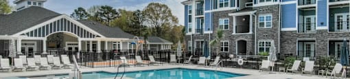 a large pool with chairs in front of a building