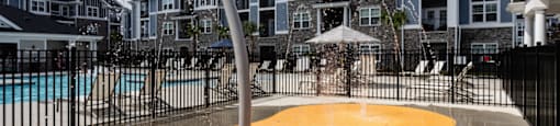 a water playground in front of a pool with apartments in the background