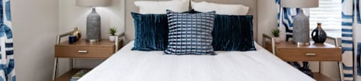 a bedroom with a bed and blue and white pillows and a sunburst mirror