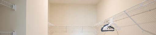 a spacious closet in a bedroom with white walls and a shower curtain