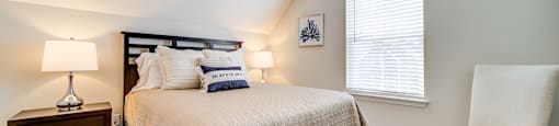 A bedroom with a bed, chair, and ceiling fan.