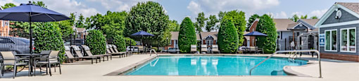 our resort style swimming pool is surrounded by chairs and umbrellas