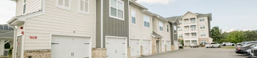 a row of white houses with cars parked in front of them