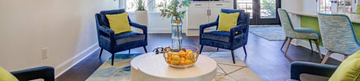 a living room with blue chairs and a round table and a chandelier