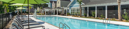 a swimming pool with lounge chairs and a building in the background