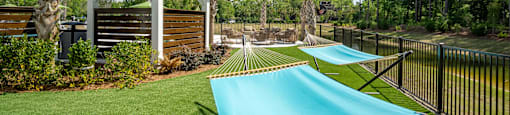 a row of hammocks in a backyard with a pool and gazebo