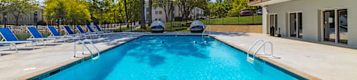 A large outdoor swimming pool with a slide and sun loungers at Enclave at 38 Twenty Two Apartments in Greensboro, NC