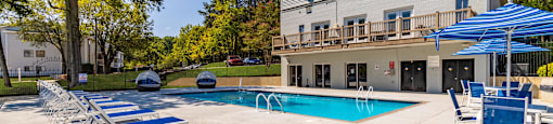 A pool area with sun loungers and a building in the background Enclave at 38 Twenty Two Apartments in Greensboro, NC