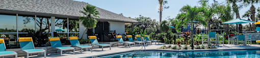 a resort style pool with lounge chairs and umbrellas
