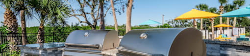 a bbq area with two grills and a table with umbrellas in the