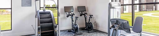 a gym with cardio equipment and windows in a building