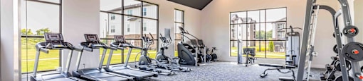 a gym with cardio equipment and windows in a building