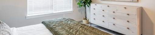 a bedroom with a bed and a dresser and a window