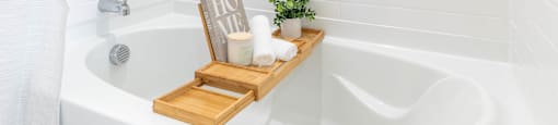a white bathtub with a wooden tray with candles and a sign in the tub