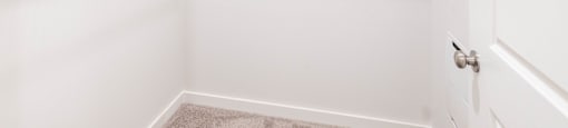 an empty closet in a home with white walls and a white door