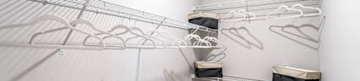 spacious closet with white walls and shelves with white mirrored closets with wire hanging racks