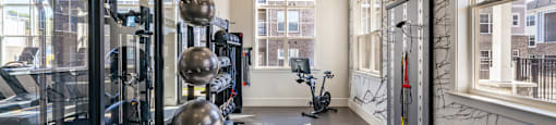 Fitness center with white walls and light brown flooring