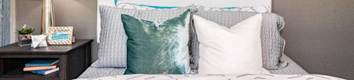 a bedroom with a bed with pillows and artwork on the wall