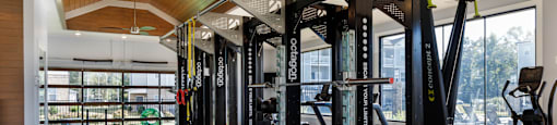 A gym with a row of squat racks and a black mat with numbers on it.