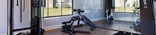 A gym with a variety of equipment including a squat rack, a leg press machine, and a treadmill.