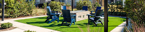 A sunny day at the apartment complex with blue chairs and a green lawn.