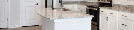 A kitchen with a granite countertop and white cabinets.