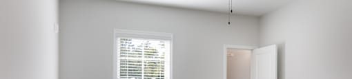 A room with a ceiling fan and a window with blinds.