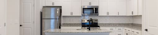 A kitchen with a white island and white cabinets.