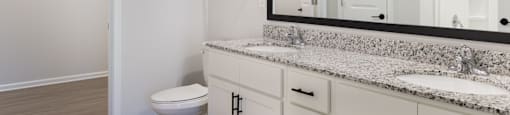 A white bathroom with a toilet, sink, and mirror.