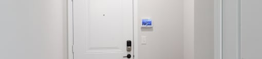 A white door with a black handle and a small blue square on the wall.
