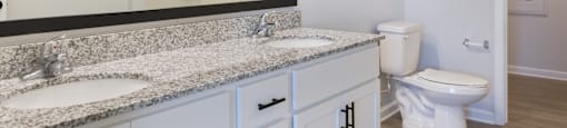A bathroom with a granite countertop and white cabinets.