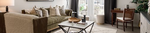 A living room with a couch, a chair, a coffee table, and a ceiling fan.