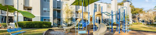 an outdoor playground with slides and swings at an apartment complex