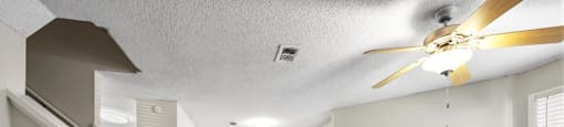an empty living room with a fireplace and a ceiling fan