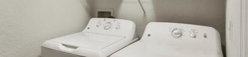 a white laundry room with two washes and a dryer