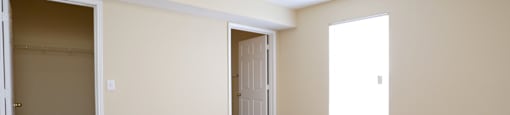 an empty living room with a closet and a ceiling fan