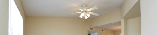 an empty living room with a fireplace and a ceiling fan