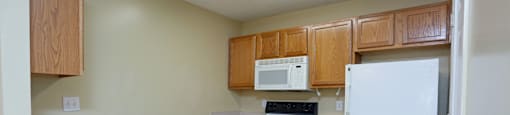 an empty kitchen with white appliances and wooden cabinets