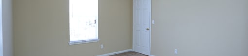 an empty living room with a door and a window