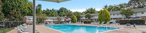 a swimming pool with chairs and an umbrella at a resort