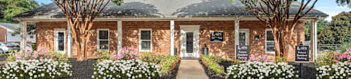 the front of a brick building with trees and flowers