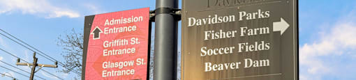 A signpost with multiple directional signs for Davidson Parks, Fisher Farm, Soccer Fields, Beaver Dam, and public parking.