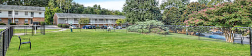 a large yard with a fence and buildings in the background