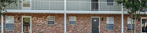 a red brick building with a balcony and a parking lot