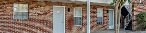 the front of a brick building with a white balcony and a white door
