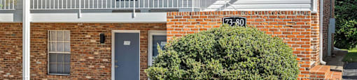 the front of a brick building with a porch and a sign on the side