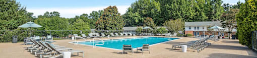 a resort style pool with lounge chairs and umbrellas