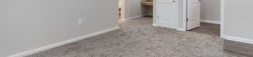 A room with white walls and a grey carpet.